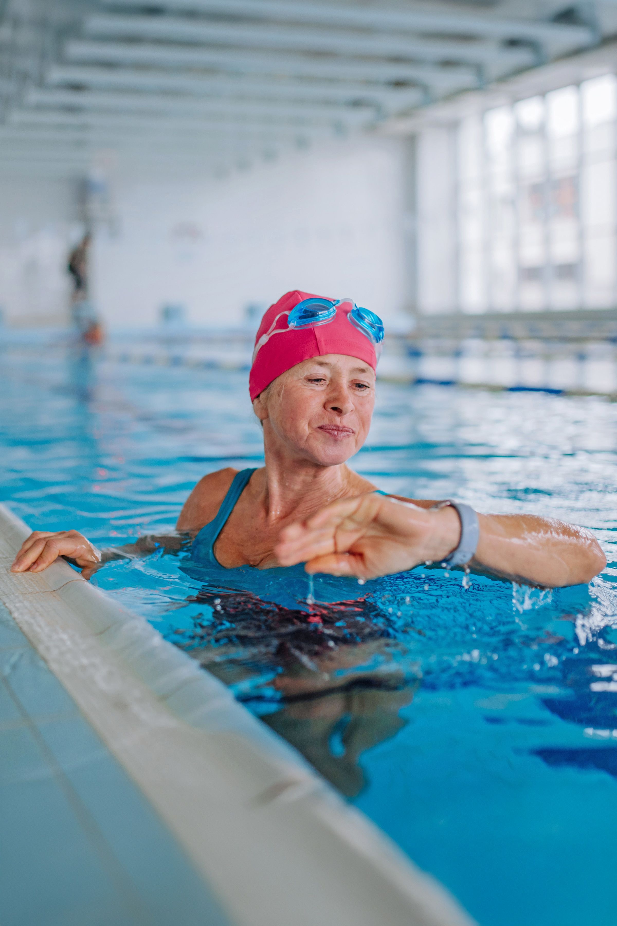 Photo of a woman in a swimming pool checking her activity tracker on her wrist.