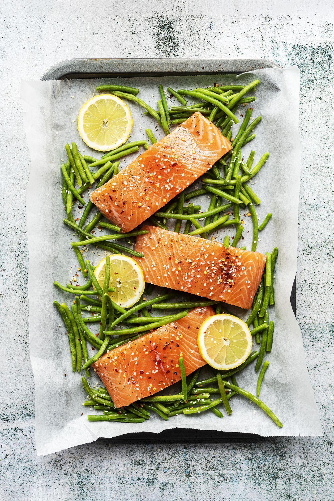 Photo of salmon on a sheet pan with green beans and lemon slices