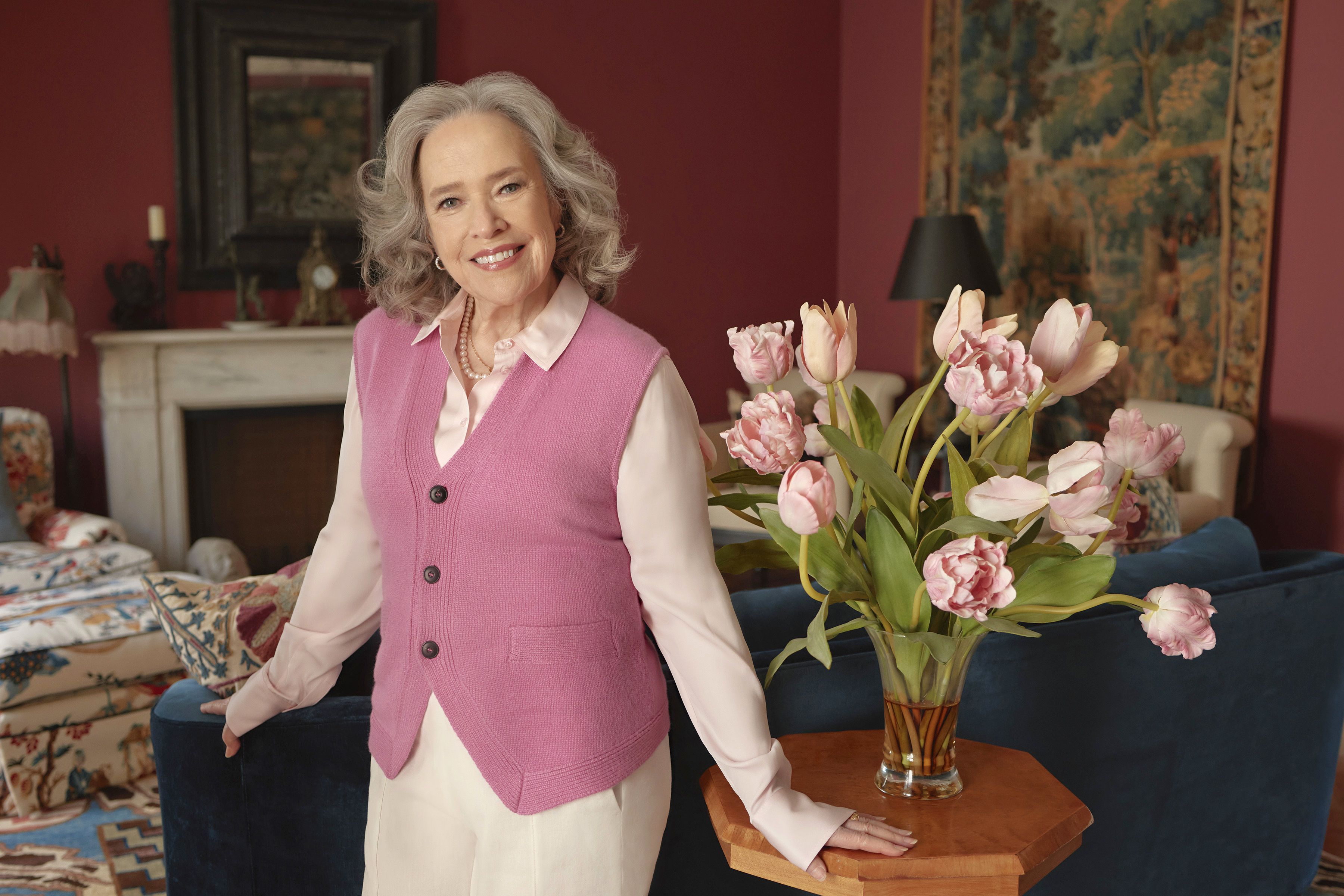 Photo of actor Kathy Bates standing in a room with colorful flowers