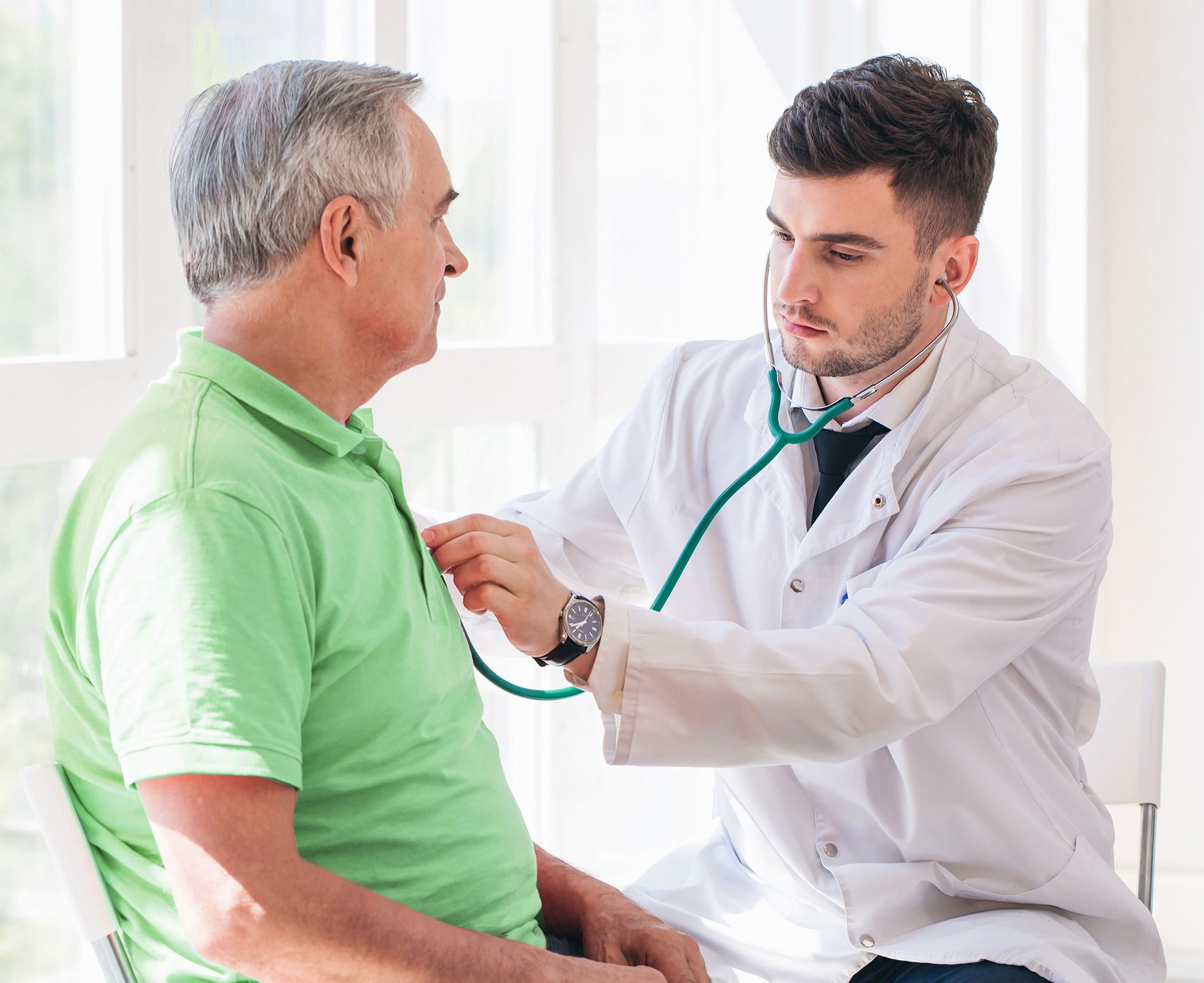 Photo of a doctor using a stethoscope to listen to a male patient's heart