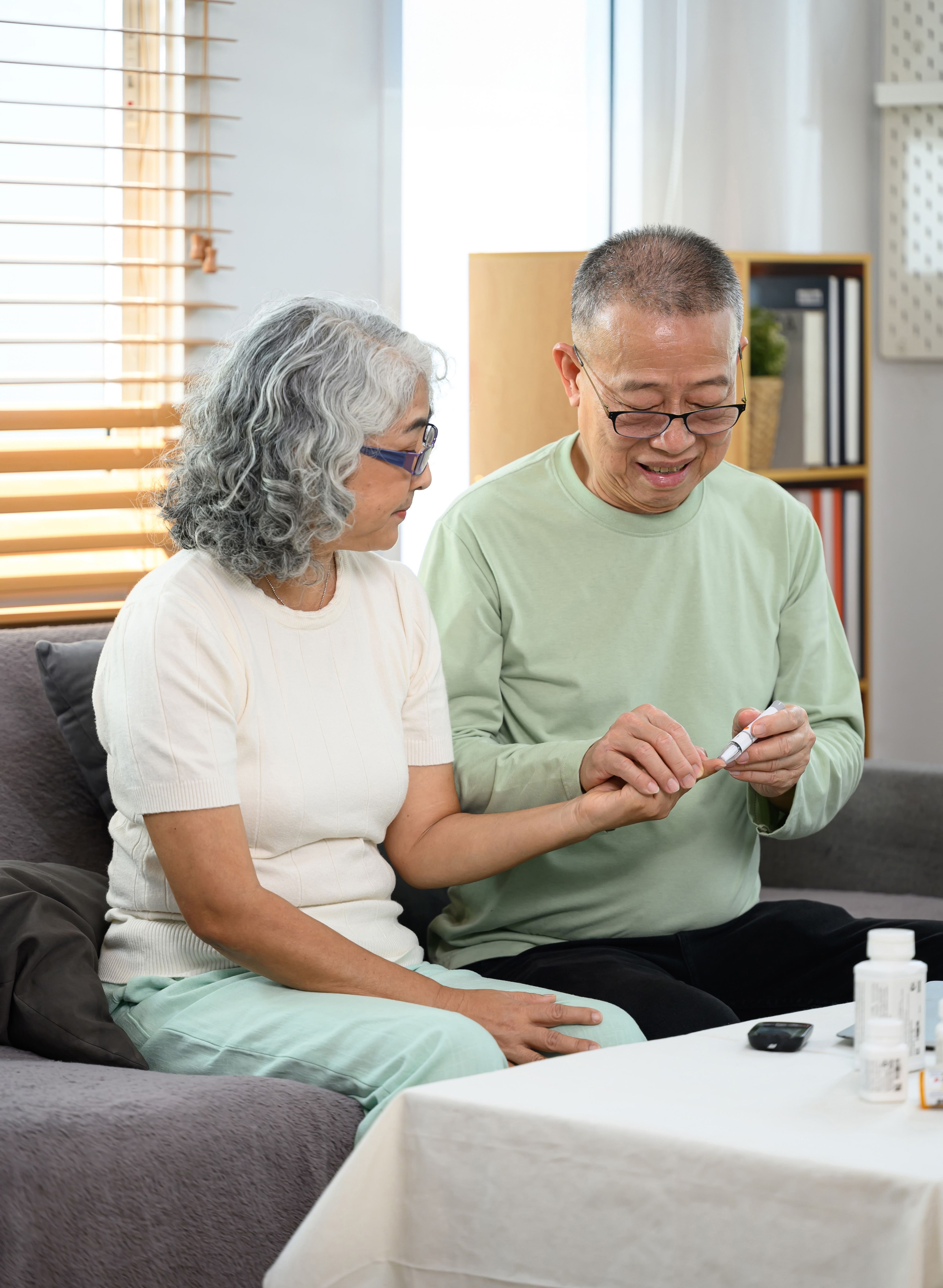 Photo of a man checking blood sugar of his diabetic wife at home