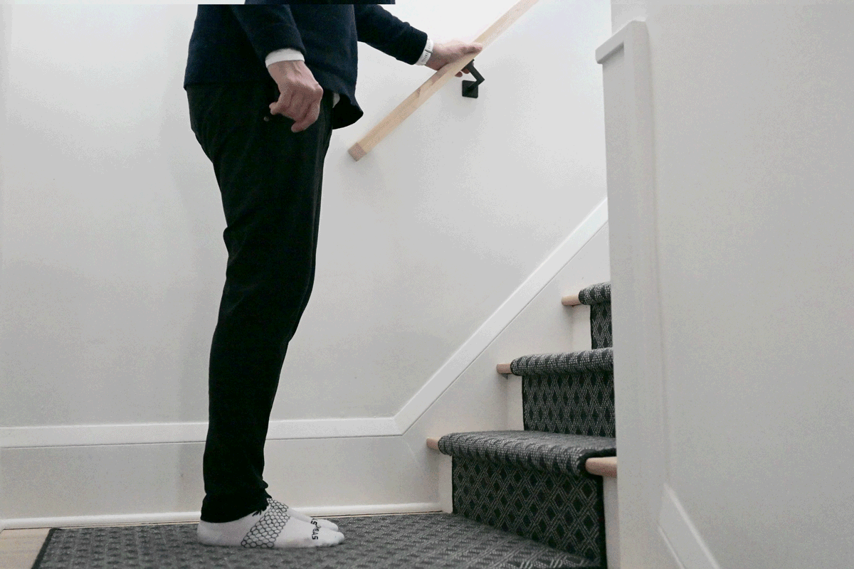 Video of a man demonstrating step-ups on a staircase in his home using a handrail.