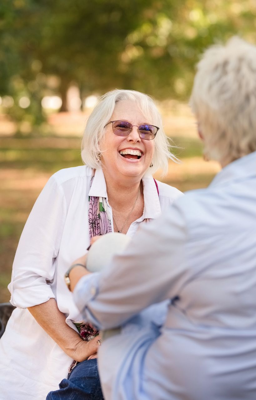 Photo of two women laughing and having a conversation in a park