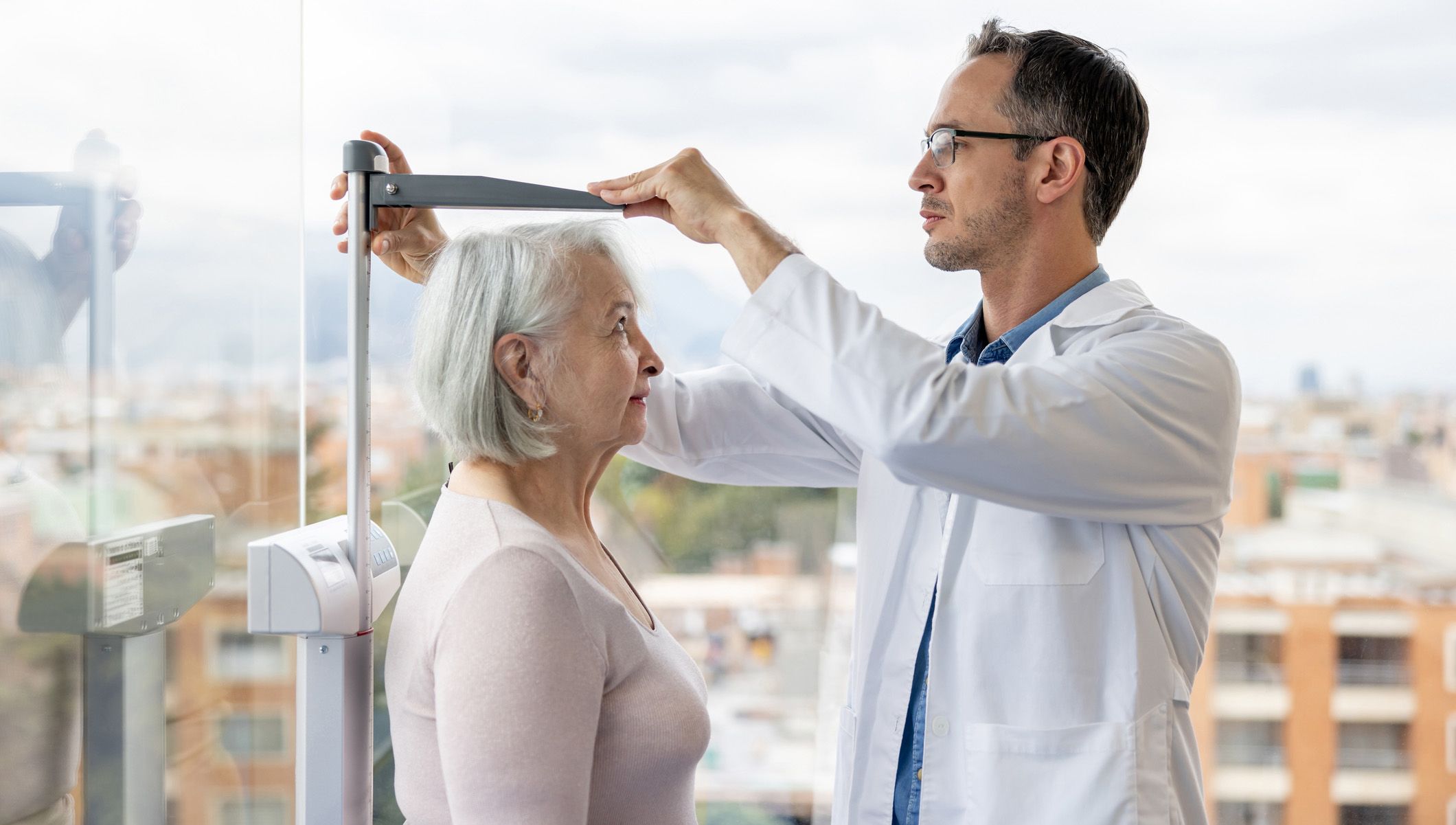 Photo of a doctor measuring an elderly woman's height