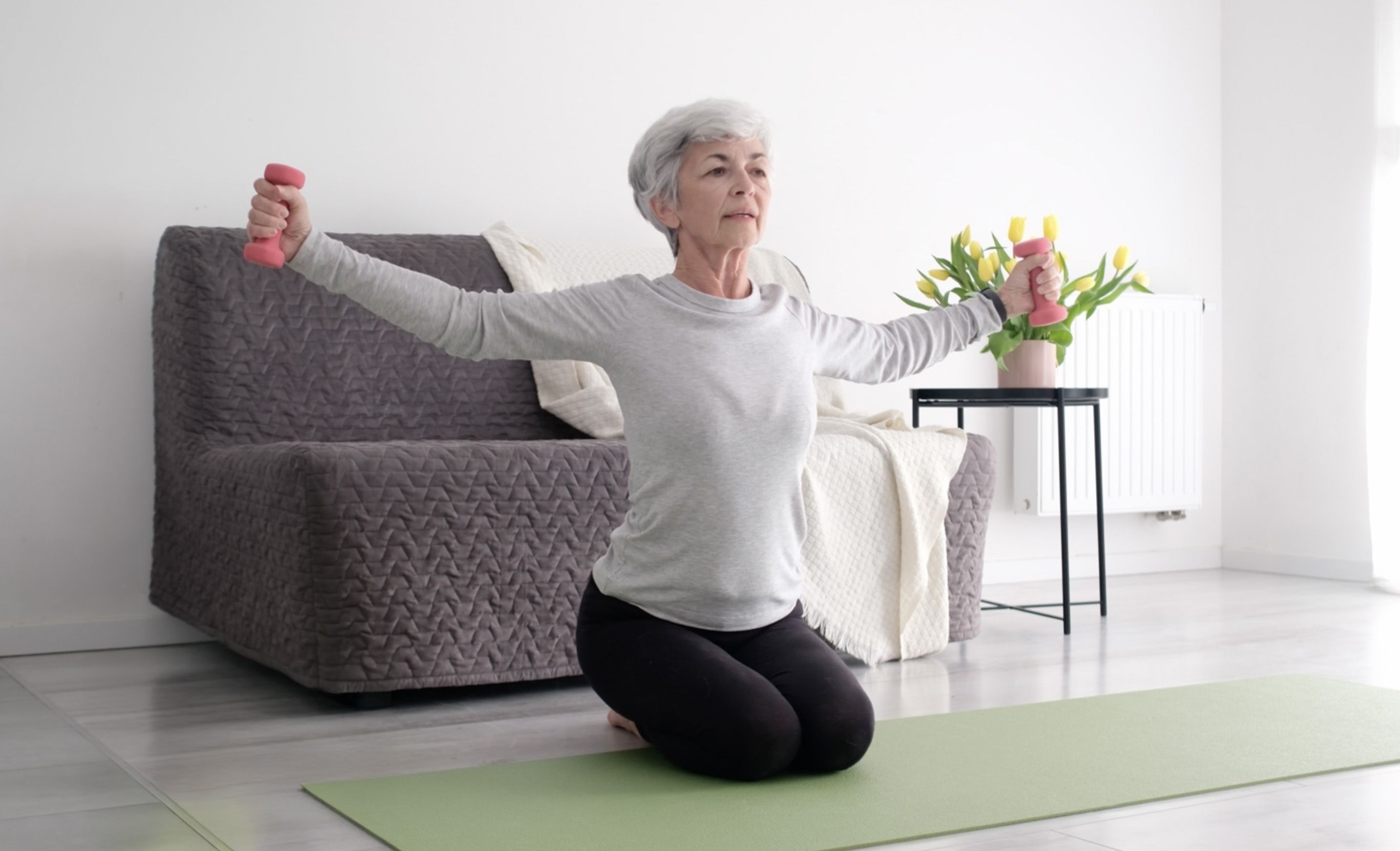 Photo of a woman at home lifting light hand weights