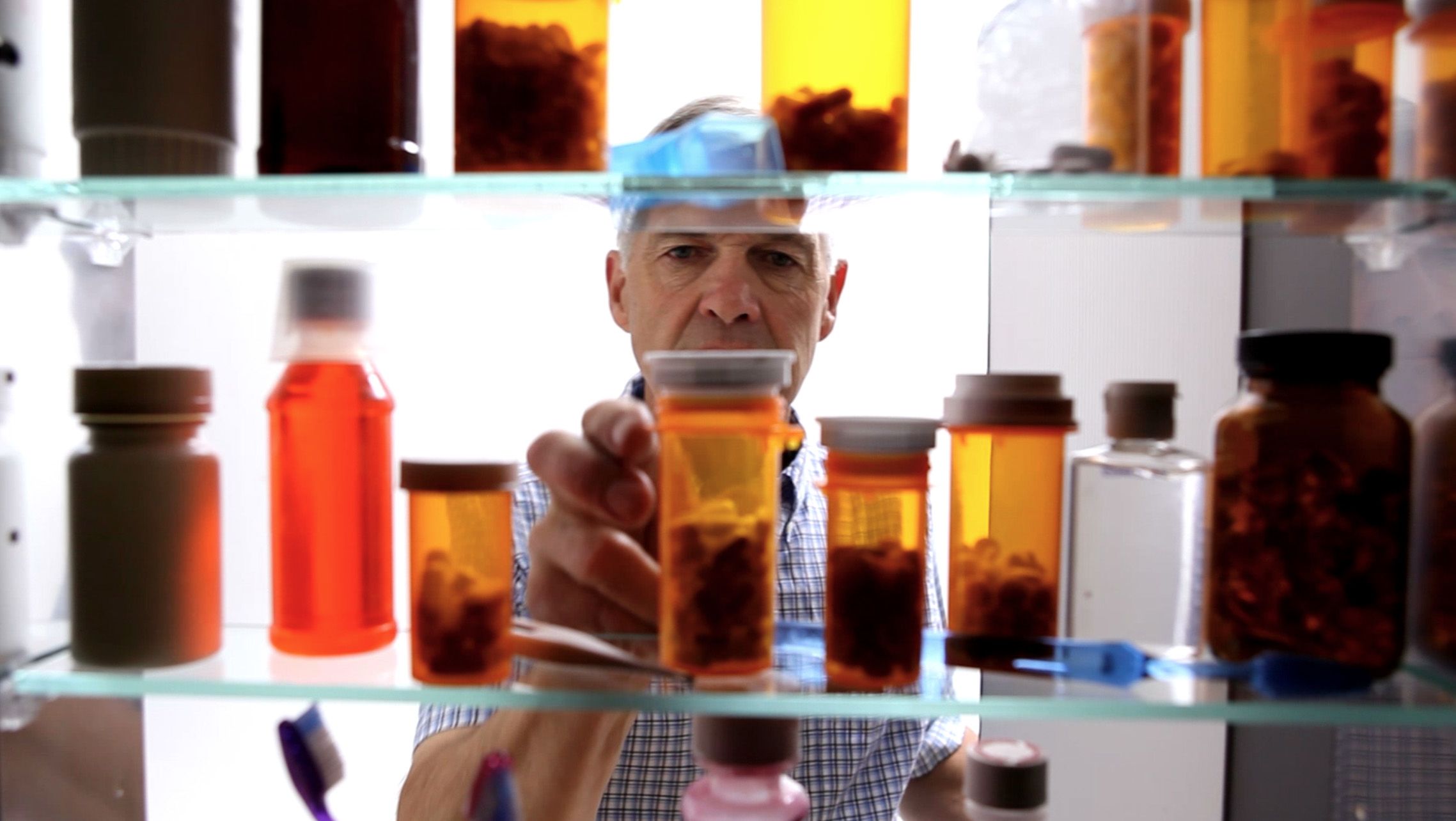 Photo of a man looking inside a medicine cabinet at home